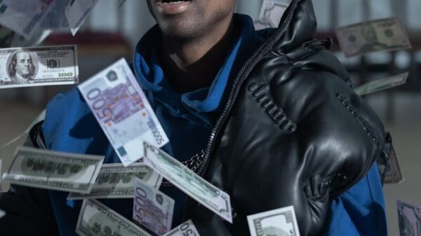 A stylish man with a leather jacket and sunglasses surrounded by floating currency notes.