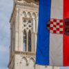 Croatian flag hangs in front of a stone tower.