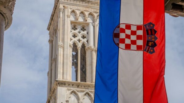 Croatian flag hangs in front of a stone tower.