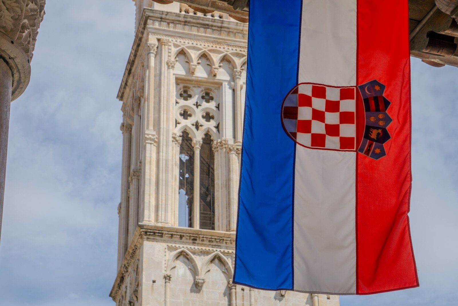 Croatian flag hangs in front of a stone tower.