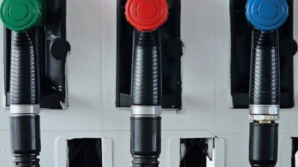 Close-up of vibrant green, red, and blue gas pump handles at a station.