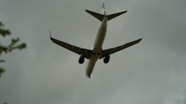A commercial airplane approaching for landing against a backdrop of cloudy skies, seen from below.