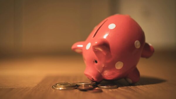 A red ceramic piggy bank with polka dots surrounded by coins, symbolizing savings and finance.