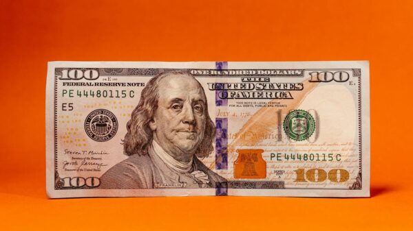 Detailed photo of a 100 dollar bill against a vibrant orange background, perfect for finance themes.