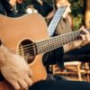 Close-up of a man playing an acoustic guitar at an outdoor concert, capturing the essence of live music.