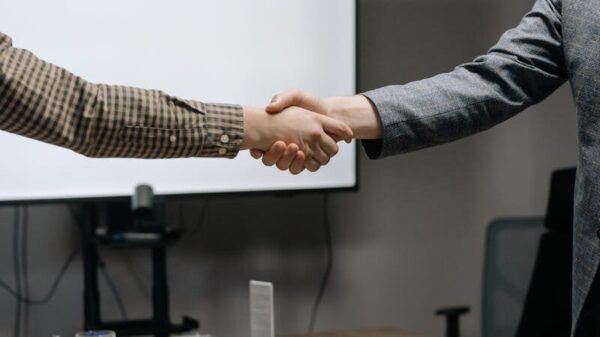 Two business professionals shaking hands in a modern meeting room, symbolizing successful collaboration.