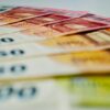 A close-up image of euro banknotes in various denominations spread out, showcasing currency details.