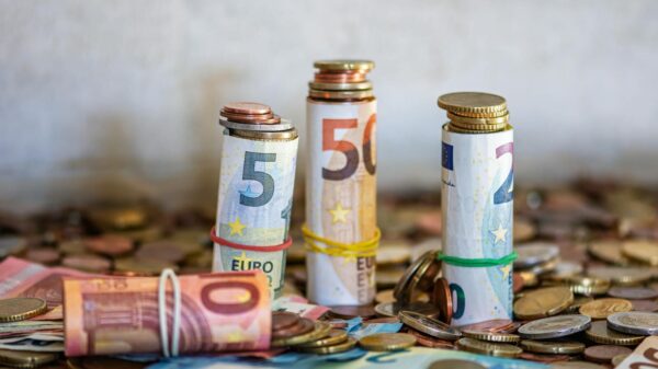 Close-up of rolled Euro banknotes and coins on a table, symbolizing finance and savings.