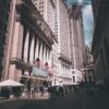View of New York Stock Exchange on a busy day with American flags and skyscrapers.