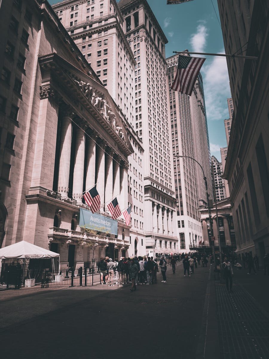 View of New York Stock Exchange on a busy day with American flags and skyscrapers.