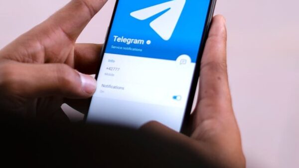 Close-up of hands holding a smartphone with the Telegram app open on the screen.