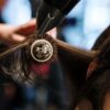 Close-up of a hairstylist styling hair with a brush and dryer in a salon setting.