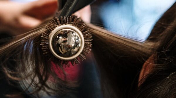 Close-up of a hairstylist styling hair with a brush and dryer in a salon setting.