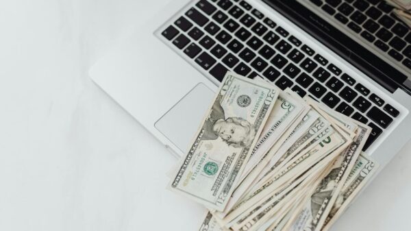 A stack of US dollar bills on a laptop keyboard representing online finance and budgeting.