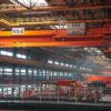 Spacious factory interior featuring large overhead cranes and metal walkways.