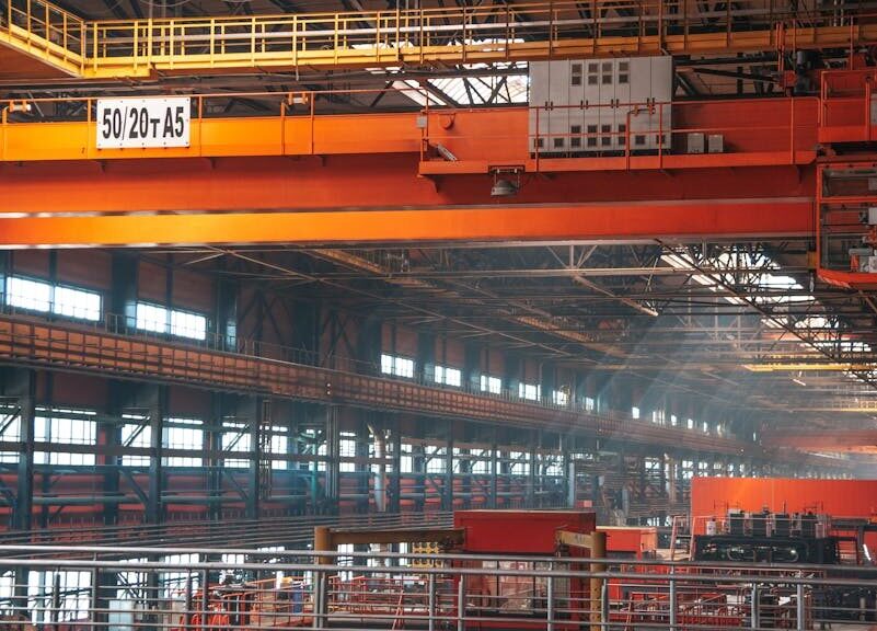 Spacious factory interior featuring large overhead cranes and metal walkways.