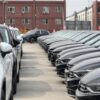 A view of modern cars neatly parked in an industrial lot on a cloudy day.