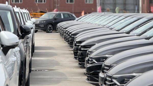 A view of modern cars neatly parked in an industrial lot on a cloudy day.