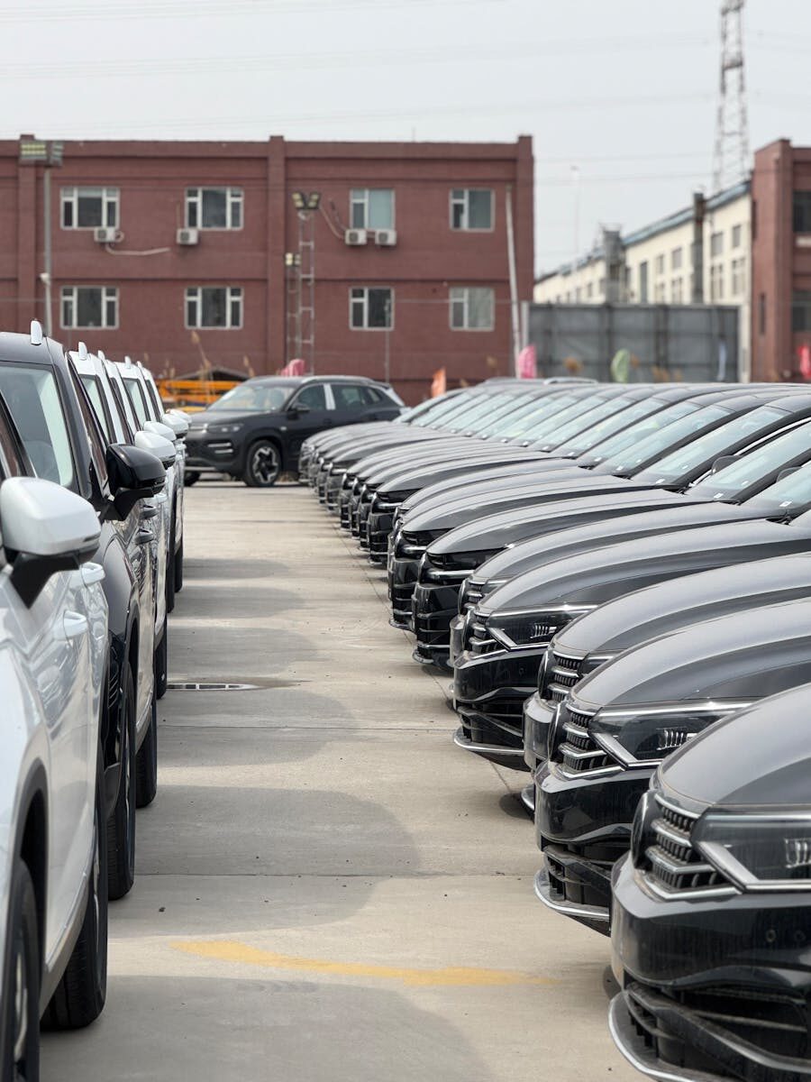 A view of modern cars neatly parked in an industrial lot on a cloudy day.