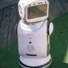 A modern robot stands on grass and wooden flooring, showcasing cutting-edge technology.