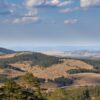 Aerial view of the rolling hills and forests of Zlatibor, Serbia, under a clear sky.