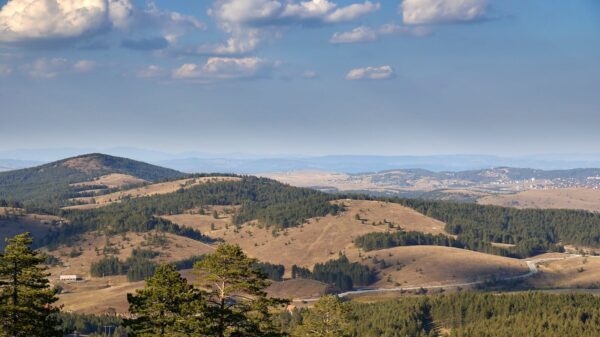 Aerial view of the rolling hills and forests of Zlatibor, Serbia, under a clear sky.