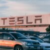 Tesla factory with parked cars during sunset, showcasing modern automotive industry vibes.