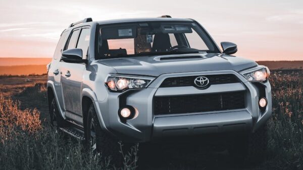 Silver Toyota SUV driving on a dirt road with sunset background, ideal for travel themes.
