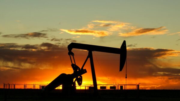 Dramatic silhouette of an oil pump jack against a vibrant sunset sky, emphasizing energy extraction.