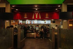 A bustling scene at a McDonald's restaurant counter with customers and staff in an indoor setting.