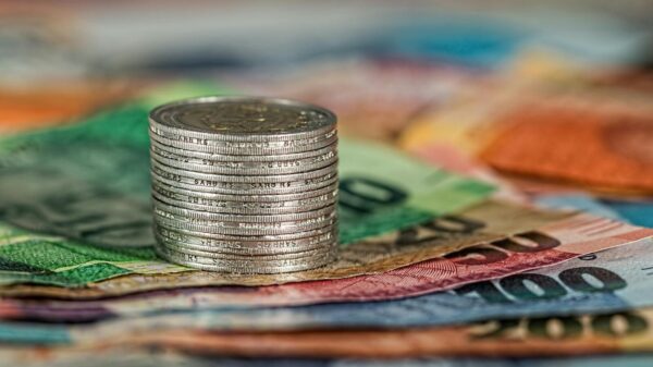 A stack of coins on top of various colored banknotes, symbolizing finance and currency.