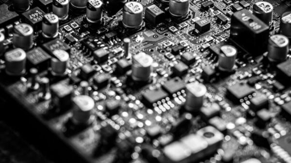 Detailed black and white close-up of an electronic circuit board with capacitors and transistors.