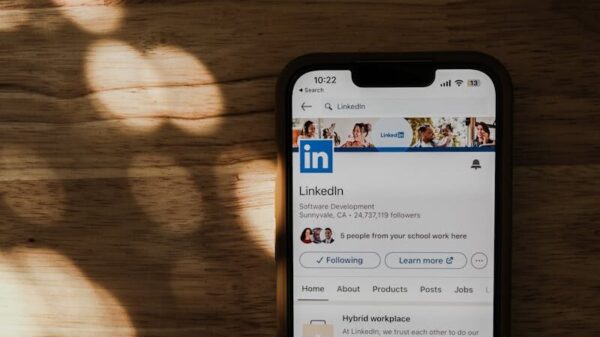 Smartphone on a wooden table showing LinkedIn app in natural light.