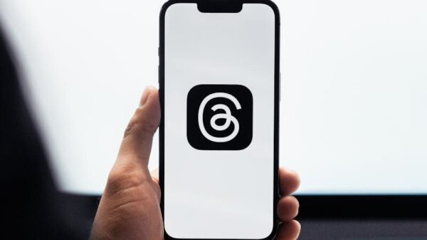 Close-up of a person holding a smartphone displaying Meta's threads logo.