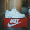 Stylish white sneaker displayed on a red Nike shoebox indoors. Perfect for fashion enthusiasts.