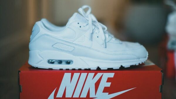 Stylish white sneaker displayed on a red Nike shoebox indoors. Perfect for fashion enthusiasts.