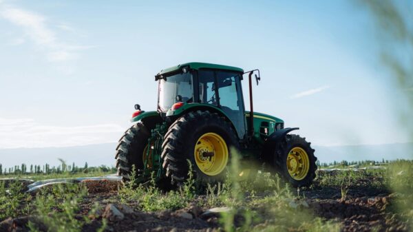 A vibrant green tractor on a farm in Mendoza, Argentina, under clear blue skies.