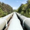 Large industrial pipeline traversing through a green forest in Geesthacht, Germany.