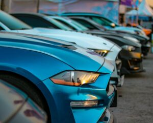A close-up view of colorful sports cars lined up in an outdoor auto show, showcasing their sleek designs.