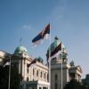 Serbian parliament building with national flags on a clear day.