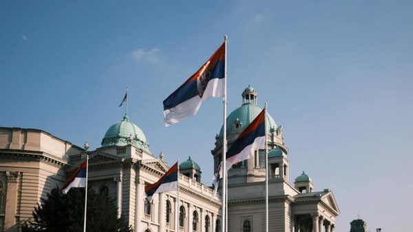 Serbian parliament building with national flags on a clear day.