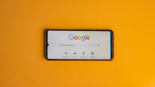 Smartphone displaying Google search page on a vibrant yellow background.