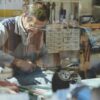 An experienced shoemaker working in a traditional workshop, surrounded by tools and materials.