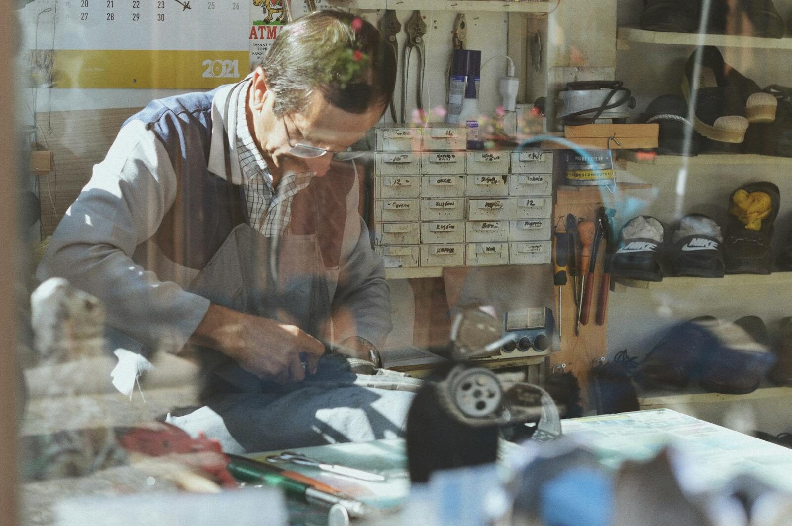 An experienced shoemaker working in a traditional workshop, surrounded by tools and materials.