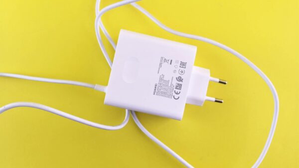 White USB charger with cable on a vibrant yellow surface, highlighting tech accessory design.