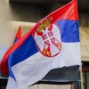 Close-up of a waving Serbian flag against urban backdrop in Belgrade city.