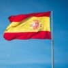 Vibrant Spanish flag waving proudly against a clear blue sky, symbolizing national pride.