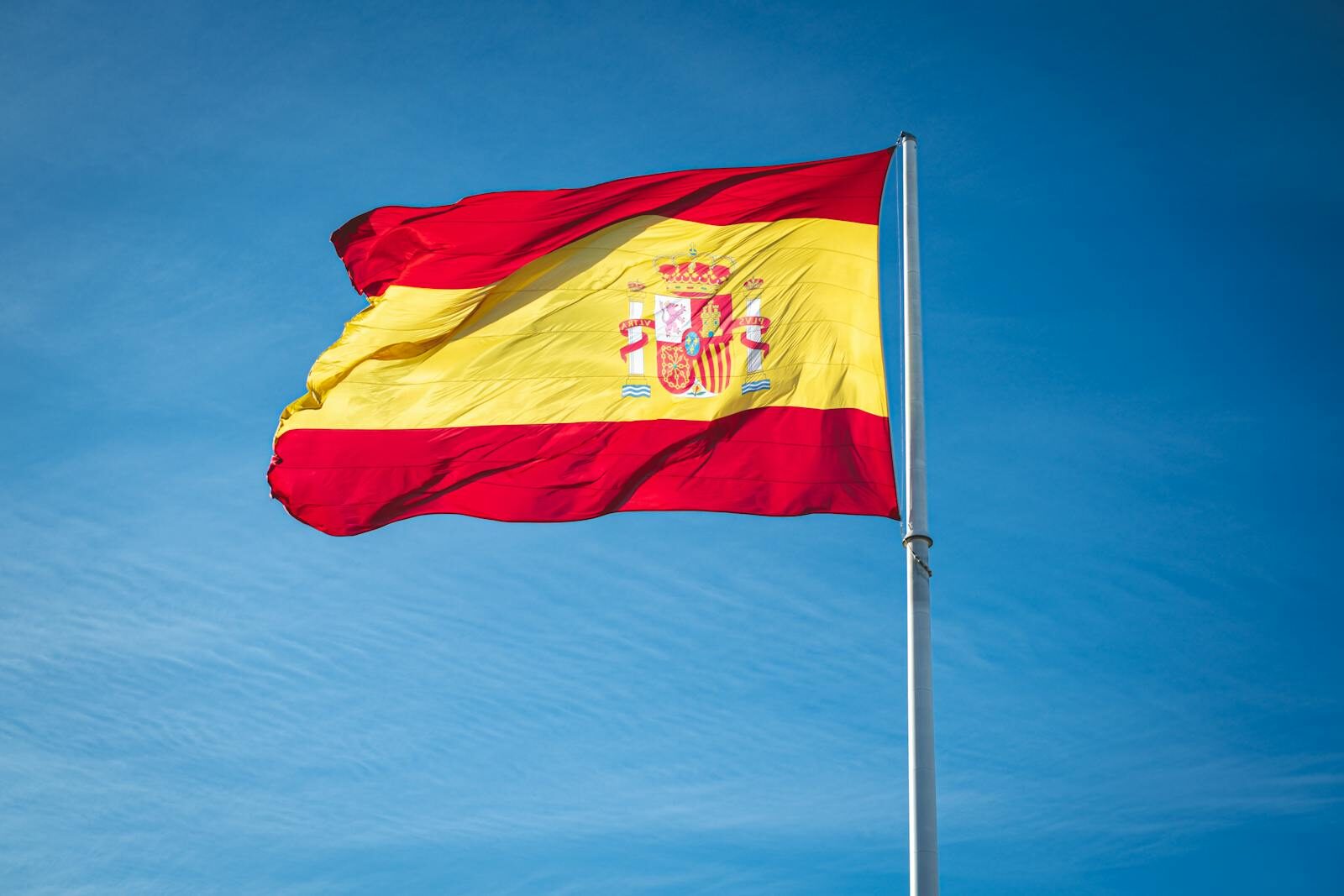Vibrant Spanish flag waving proudly against a clear blue sky, symbolizing national pride.