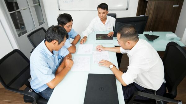 Four professionals discuss plans around an office table, fostering collaboration and teamwork.