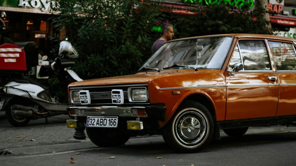 Classic orange car parked on a bustling Istanbul street with a nostalgic ambiance.